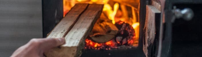 personne alimentant au bois un poêle