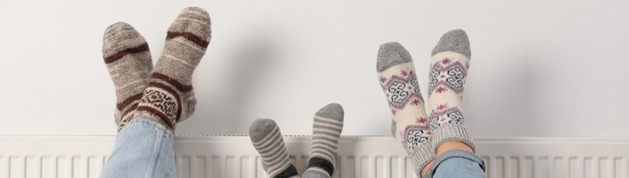 trois paires de pieds en chaussettes posés sur un radiateur