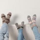 trois paires de pieds en chaussettes posés sur un radiateur