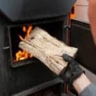 personne alimentant sa chaudière avec du bois