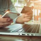 personne tenant un smartphone et une carte de paiement