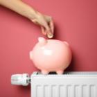 personne mettant un pièce dans une tirelire cochon sur un radiateur