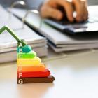 homme écrivant sur un planning et devant une décoration d'une maison surélevée d'un gradué diagnostic de performance énergétique