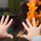mains d'un enfant posées sur la vitre d'un poêle