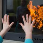 mains d'un enfant posées sur la vitre d'un poêle
