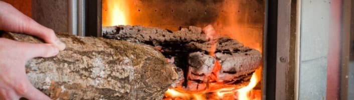 personne alimentant sa cheminée avec du bois