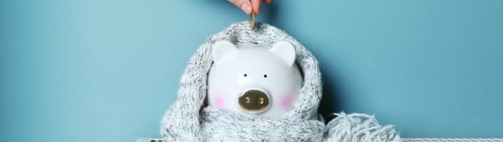 une pièce déposée dans une tirelire cochon avec écharpe