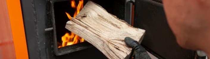 personne alimentant sa chaudière avec du bois