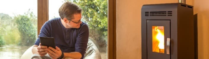 un homme devant son smartphone qui observe son poêle à granules