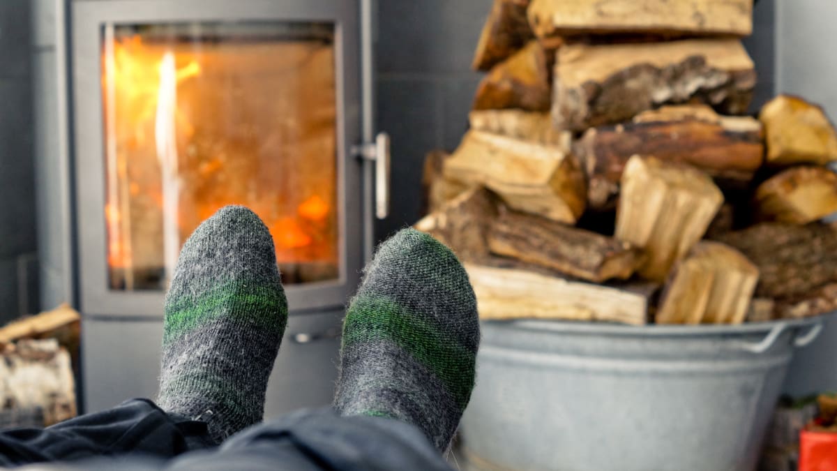 personne chauffant ses pieds au poêle