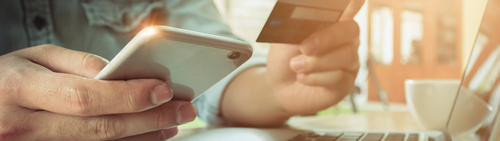 personne tenant un smartphone et une carte de paiement
