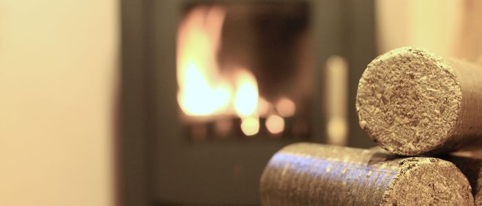 Bûches en bois compressé et en arrière plan une cheminée