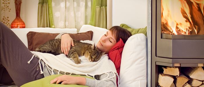 une femme avec son chat allongés près d'un poêle