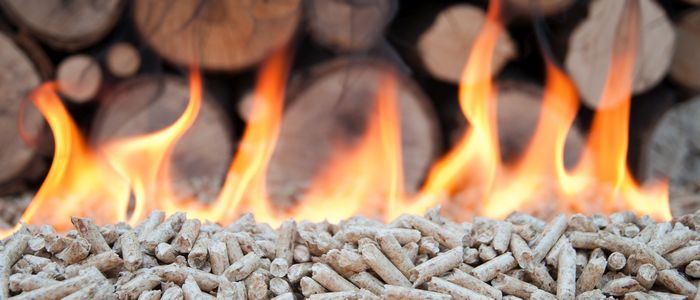 bois granulés enflammés avec en arrière plan des bûches de bois entassées