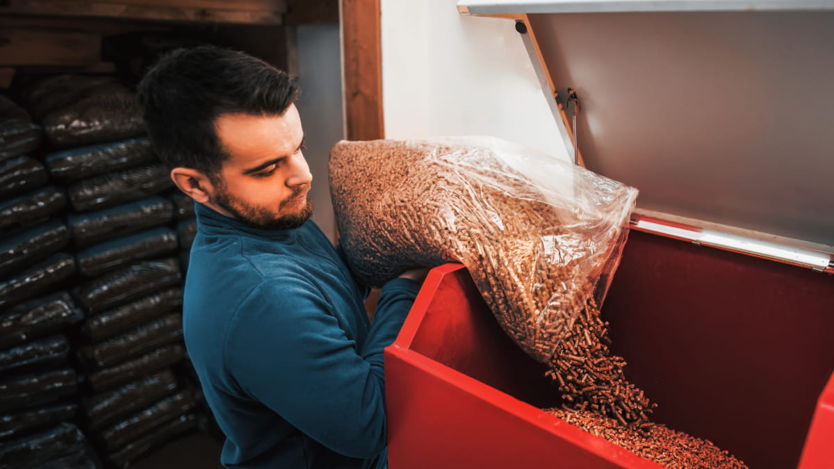homme remplissant de pellets le bac d'une chaudière