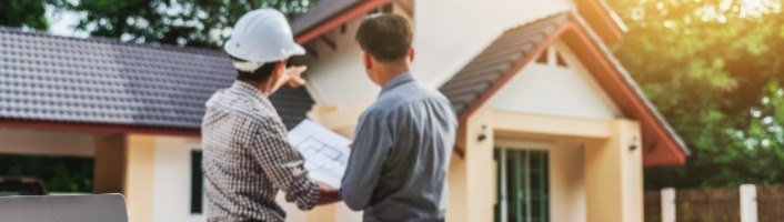 artisan de chantier montrant une maison du doigt et serrant la main d'un client