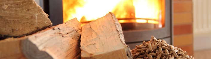 une bûche et des pellets devant un poêle allumé