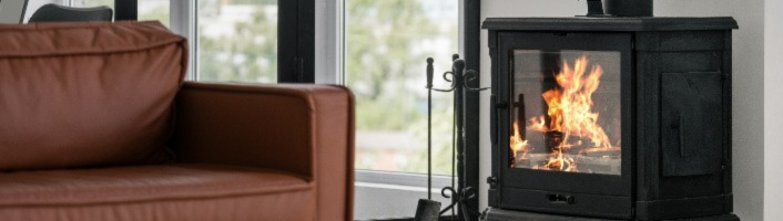 salon avec un fauteuil proche d'un poêle allumé