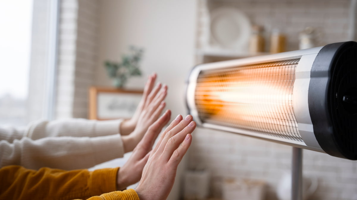 personnes se chauffant les mains via radiateur électrique