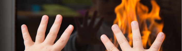 mains d'un enfant posées sur la vitre d'un poêle